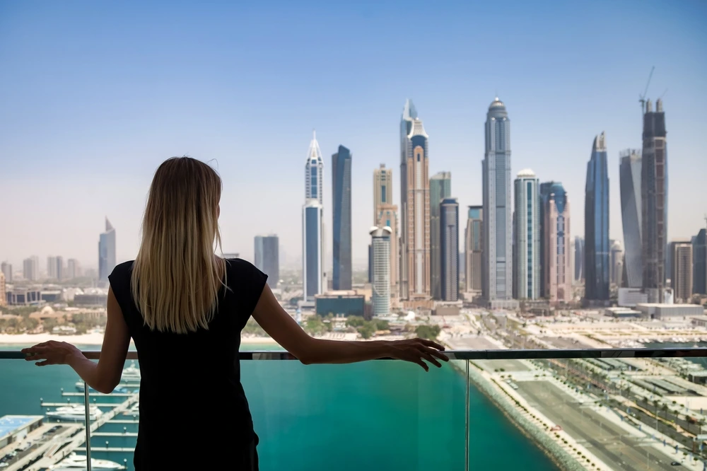 young woman in black on balcony with view of Dubai skyscrapers